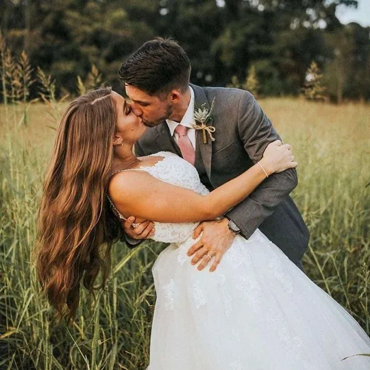 A couple kissing in the tall grass of the Field G Hay Field at this working farm near Sevierville